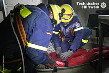 Eine verletzte Person wird auf der Bergeschleppe eingebunden, sodass diese durch den Tunnel gerettet werden kann. (Foto: THW / Daniel Claus)